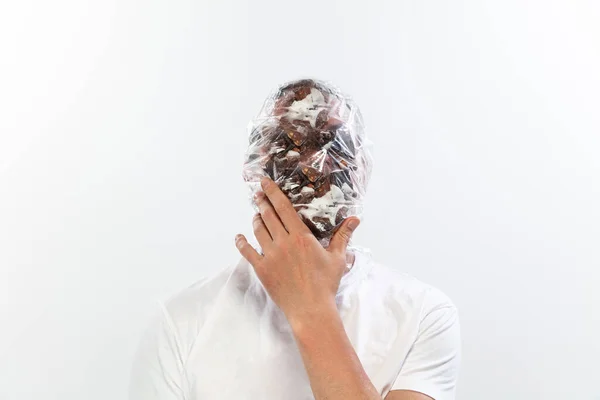 Male face covered with oilcloth, cellophane and unhealthy food, hard to breathe. People lost their faces, cant notice the environmental pollution made by themself. — Stock Photo, Image