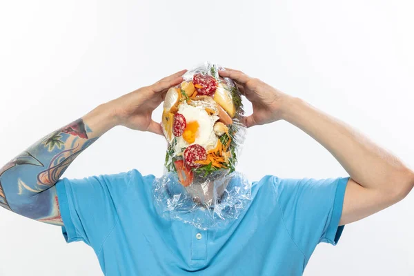 Male face covered with oilcloth, cellophane and unhealthy food, hard to breathe. People lost their faces, cant notice the environmental pollution made by themself. — Stock Photo, Image