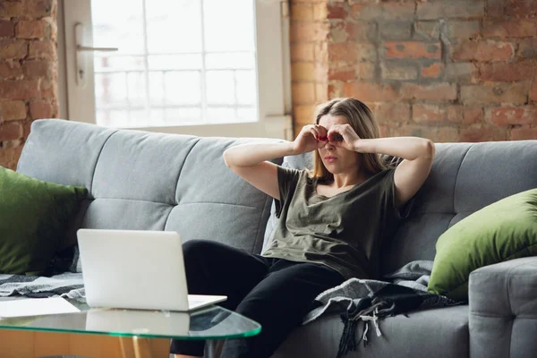 Молодая женщина, деловая женщина, работающая или занимающаяся дома с ноутбуком, сидящим на диване. Акцентирован, сконцентрирован. Copyspace . — стоковое фото