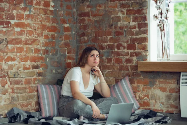Молодая женщина, деловая женщина работает или учится дома с ноутбуком рядом с окном. Акцентирован, сконцентрирован. Copyspace . — стоковое фото