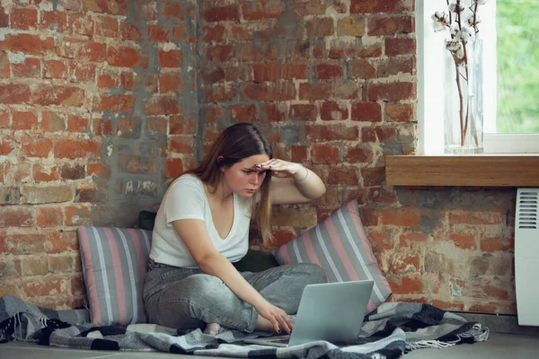 Fiatal nő, üzletasszony, aki otthon dolgozik vagy tanul laptoppal az ablak közelében. Figyelmes, koncentrált. Másolótér. — Stock Fotó