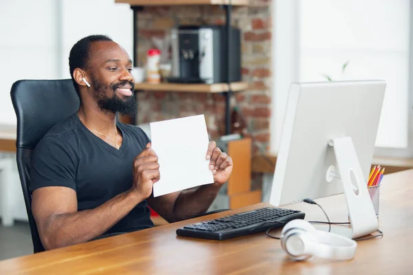 Junger Mann, Geschäftsmann im Büro, Blick auf leeren schwarzen Computerbildschirm, Monitor, leeres weißes Laken, Whiteboard. Kopierraum. — Stockfoto