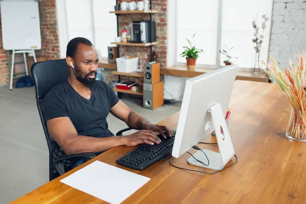 Joven, hombre de negocios trabajando en la oficina, mirando en la pantalla de la computadora, monitor, con la hoja blanca en blanco, pizarra blanca cerca de él. Espacio de copia . — Foto de Stock