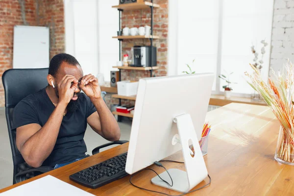 Молодий чоловік, бізнесмен, який працює в офісі, дивлячись на екран комп'ютера, монітор, з чистим білим аркушем, біла дошка поруч з ним. Копіспазмі . — стокове фото