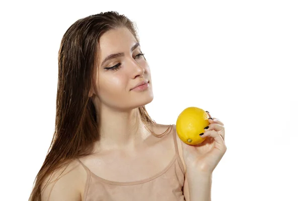 Secretos juveniles. Hermosa joven con limón sobre fondo blanco. Cosméticos y maquillaje, tratamiento natural y ecológico, cuidado de la piel . — Foto de Stock