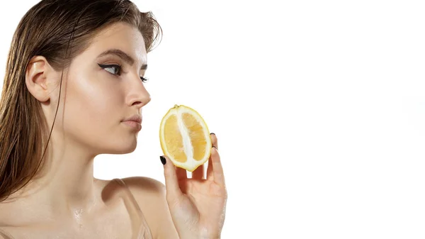 Des vitamines. Belle jeune femme avec une tranche de citron sur fond blanc. Cosmétiques et maquillage, traitement naturel et écologique, soin de la peau. Flyer avec copyspace . — Photo