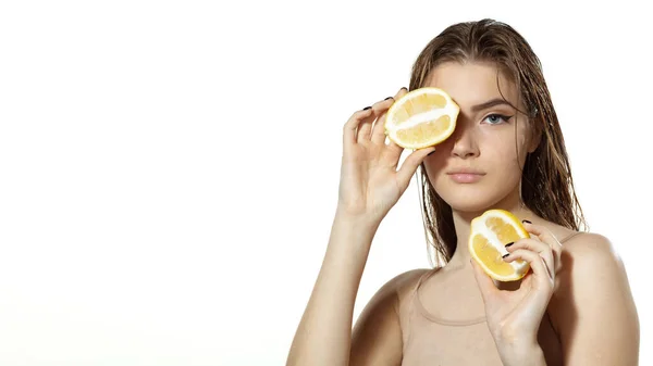 Vitaminas. Hermosa joven con rodaja de limón sobre fondo blanco. Cosméticos y maquillaje, tratamiento natural y ecológico, cuidado de la piel. Folleto con copyspace . — Foto de Stock