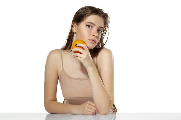 Skincare. Beautiful young woman with orange over white background. Cosmetics and makeup, natural and eco treatment. — Stock Photo, Image