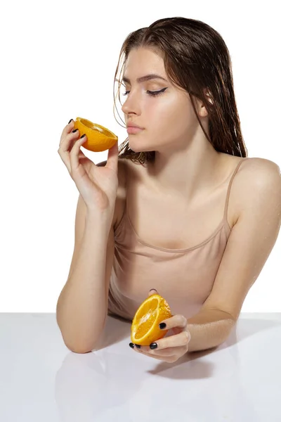 Orgánica. Hermosa joven con rodajas de naranja sobre fondo blanco. Cosméticos y maquillaje, tratamiento natural y ecológico, cuidado de la piel . — Foto de Stock