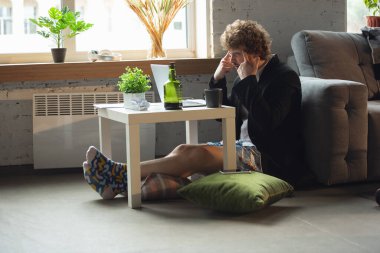 Pantolonsuz ama ceketli genç bir adam bilgisayar ve dizüstü bilgisayarla çalışıyor. Coronavirus sırasında uzak ofis, iç çamaşırlarıyla eğlenceli ve rahat bir iş.