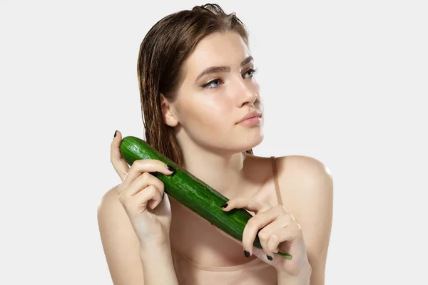 Jeugdgeheimen. Close-up van mooie jonge vrouw met komkommer over witte achtergrond. Cosmetica en make-up, natuurlijke en eco-behandeling, huidverzorging. — Stockfoto