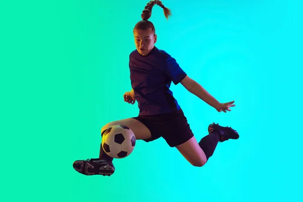 Female soccer, football player kicking ball, training in action and motion with bright emotions isolated on gradient background — Stock Photo, Image