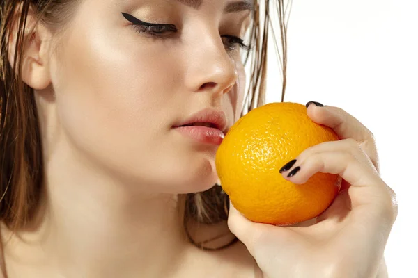 Primer plano de hermosa mujer joven con jugosa naranja sobre fondo blanco. Cosméticos y maquillaje, tratamiento natural y ecológico, cuidado de la piel . — Foto de Stock