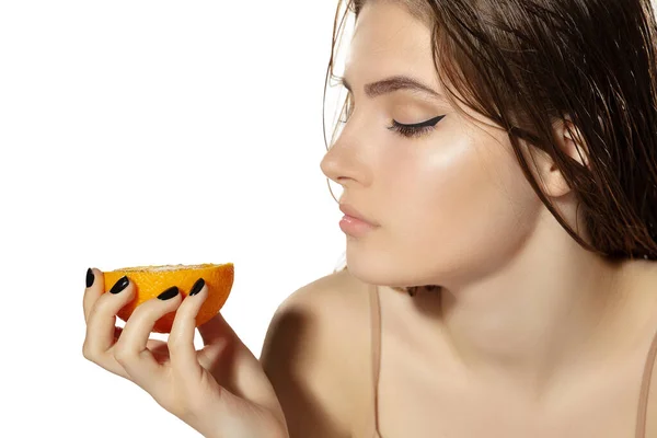 Primer plano de hermosa mujer joven con jugosa naranja sobre fondo blanco. Cosméticos y maquillaje, tratamiento natural y ecológico, cuidado de la piel . — Foto de Stock