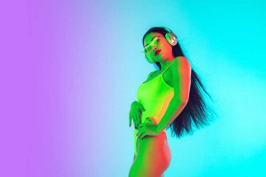 Modaya uygun mayo giymiş güzel bir kız neon ışıklarıyla izole edilmiş bir şekilde stüdyoda. Yaz, tatil köyü, moda ve hafta sonu konsepti