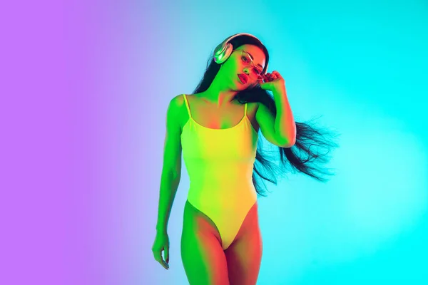 Menina bonita em maiô elegante isolado no fundo do estúdio gradiente em luz de néon. Verão, resort, moda e conceito de fim de semana — Fotografia de Stock