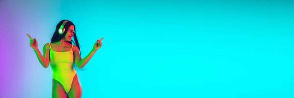 Красивая девушка в модном купальнике изолирована на градиентном фоне студии в неоновом свете. Лето, курорт, мода и концепция выходных. Флаер с копирайтом
.