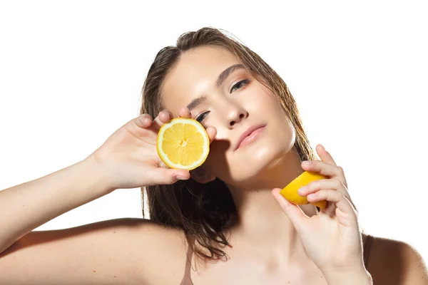 Des agrumes. Gros plan du beau visage féminin avec des tranches de citron sur fond blanc. Cosmétiques et maquillage, traitement naturel et écologique, soin de la peau . — Photo