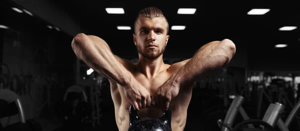 Fitness man doing a weight training by lifting heavy kettlebell — Stock Photo, Image