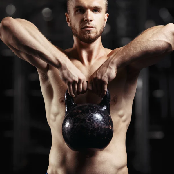 Fitness man doing a weight training by lifting heavy kettlebell — Stock Photo, Image