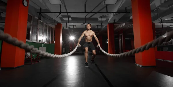 Homem de fitness trabalhando com cordas de batalha em um ginásio — Fotografia de Stock