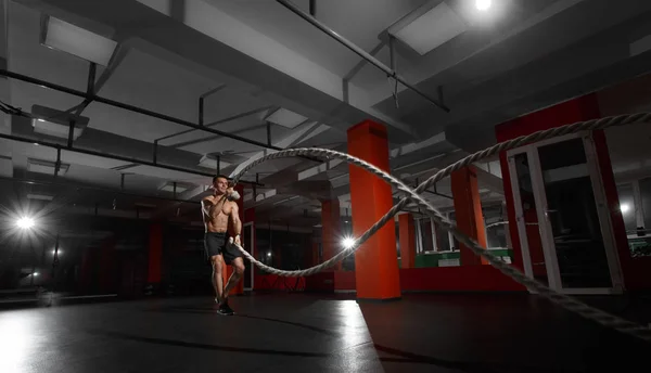 Homem de fitness trabalhando com cordas de batalha em um ginásio — Fotografia de Stock