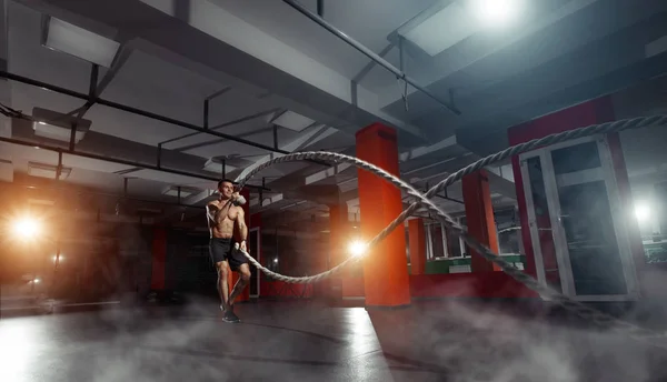 Hombre de fitness haciendo ejercicio con cuerdas de batalla en un gimnasio — Foto de Stock