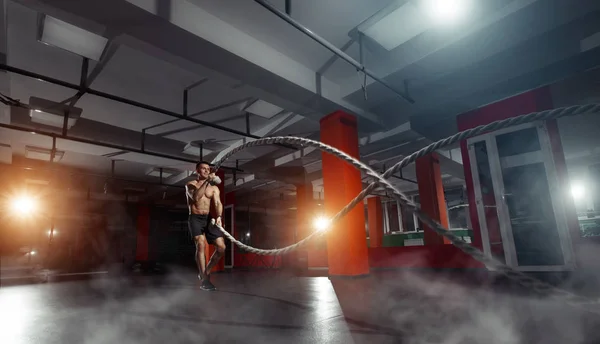 Homem de fitness trabalhando com cordas de batalha em um ginásio — Fotografia de Stock