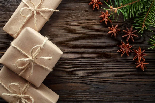 Χριστουγεννιάτικη σύνθεση σε ξύλινα φόντο με δέντρου, κουκουνάρια, αστεροειδή γλυκάνισο και κουτιά από χαρτόνι — Φωτογραφία Αρχείου