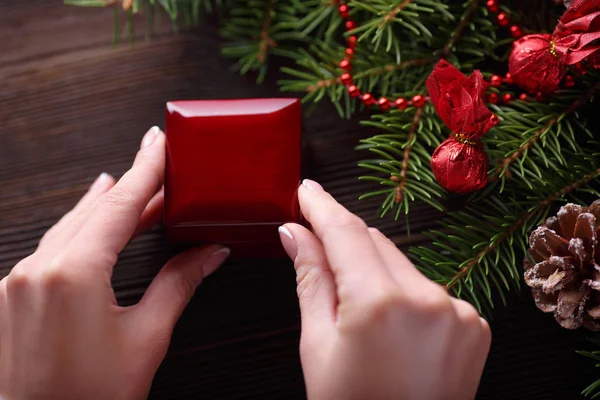 Anillo de compromiso en manos femeninas entre decoraciones navideñas sobre fondo de madera — Foto de Stock