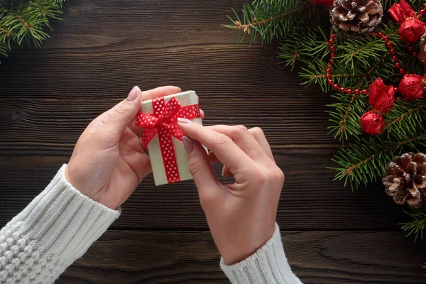 Hermosas manos femeninas sosteniendo un regalo de Navidad en caja con lazo rojo . — Foto de Stock