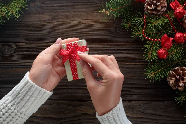 Hermosas manos femeninas sosteniendo un regalo de Navidad en caja con lazo rojo . —  Fotos de Stock