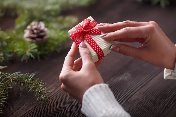 Hermosas manos femeninas sosteniendo un regalo de Navidad en caja con lazo rojo . —  Fotos de Stock