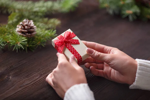 Hermosas manos femeninas sosteniendo un regalo de Navidad en caja con lazo rojo . —  Fotos de Stock