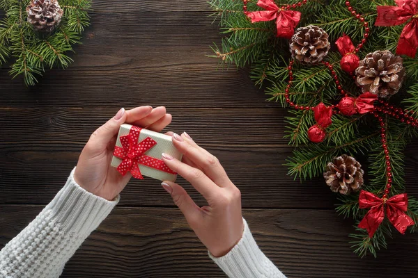 Hermosas manos femeninas sosteniendo un regalo de Navidad en caja con lazo rojo . — Foto de Stock