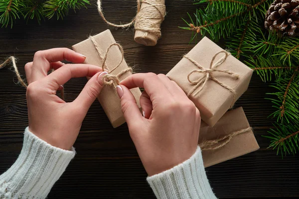 Vackra kvinnliga händer är förpackade julklapp i brunt kraftpapper. — Stockfoto