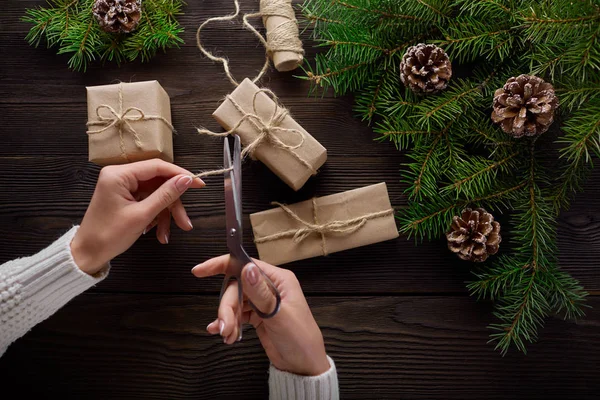 Hermosas manos femeninas se embalan regalo de Navidad en papel kraft marrón . — Foto de Stock