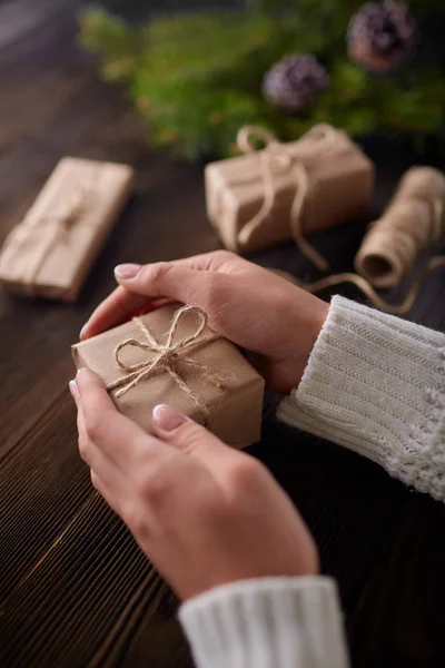 Hermosas manos femeninas se embalan regalo de Navidad en papel kraft marrón . — Foto de Stock