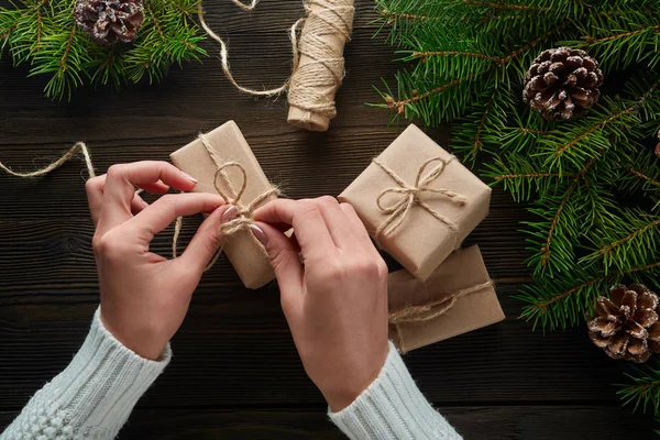 Vackra kvinnliga händer är förpackade julklapp i brunt kraftpapper. — Stockfoto