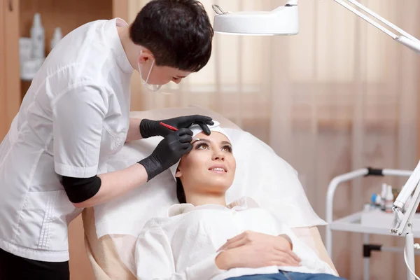 Asistente de maquillaje permanente hace procedimiento de corrección de cejas — Foto de Stock