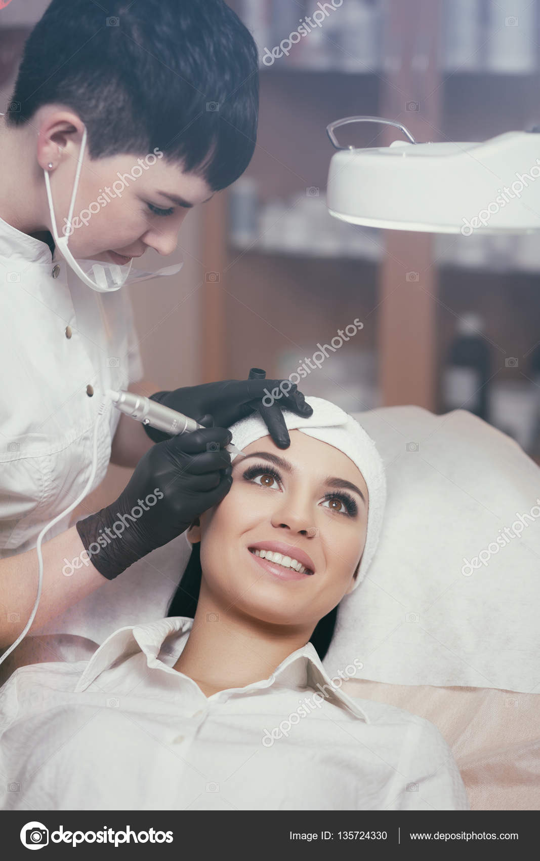 Cosmetologist applying permanent make up on eyebrows- eyebrow tattoo