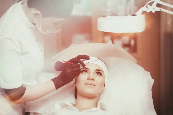 Assistente de maquiagem permanente faz procedimento de correção de sobrancelha — Fotografia de Stock