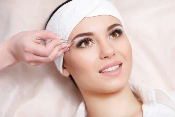 Young woman tweezing her eyebrows in beauty saloon — Stock Photo, Image