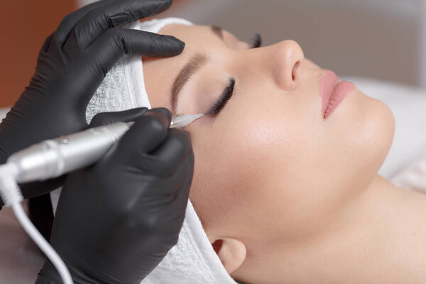 Close up cosmetologist making eyeliner permanent makeup