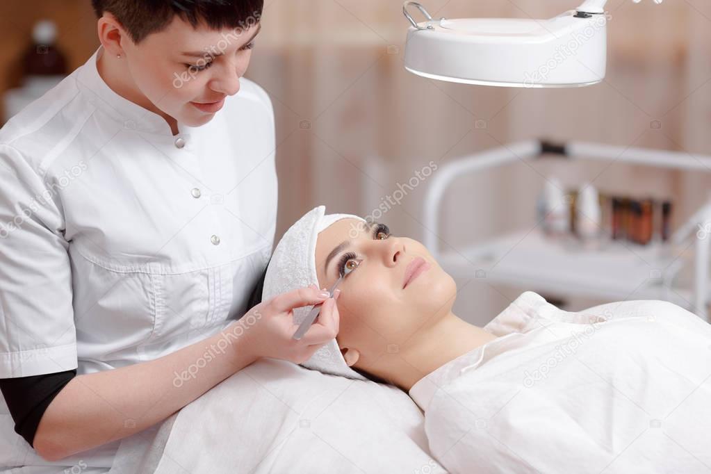 Stylist making eyelash extension for women in beauty salon.