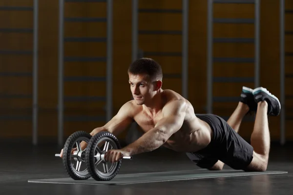 Adam tonlama tekerleği ile katta spor egzersiz yapıyor — Stok fotoğraf