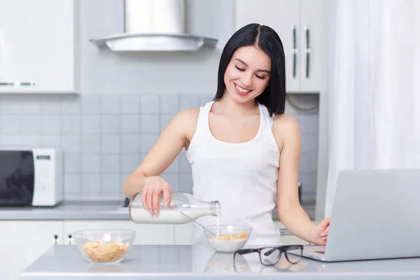 Brünette Frau gießt Milch in Eichenflocken. — Stockfoto