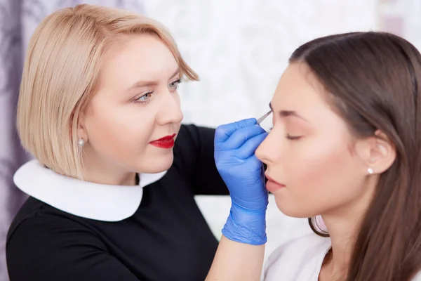 Professional gör permanent göra för klienten i salong. — Stockfoto