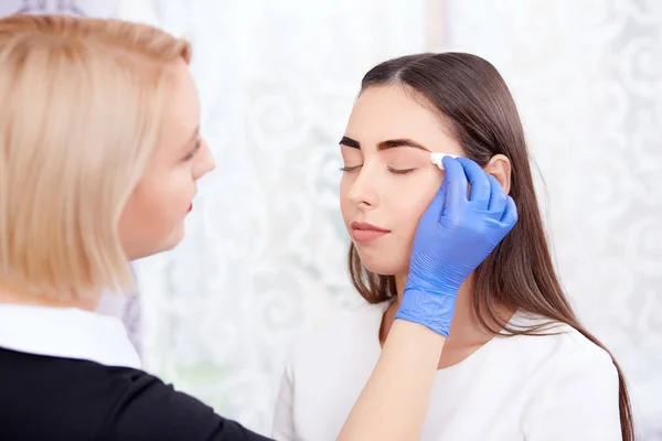 Cosmetologist limpeza rosto após a maquiagem permanente . — Fotografia de Stock