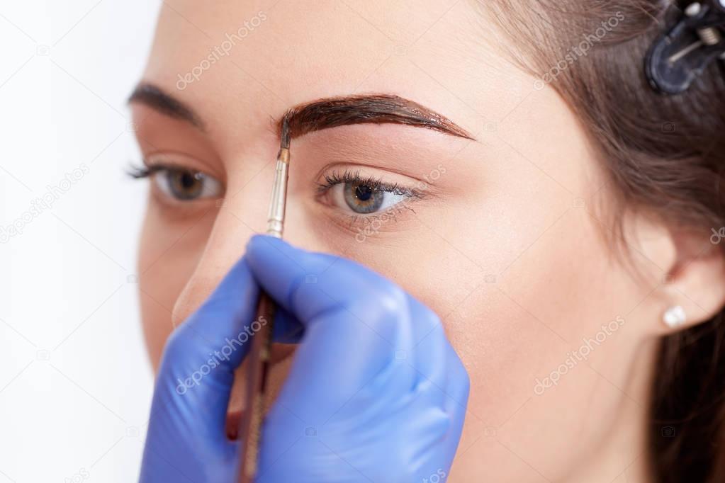 Cosmetologist applying special permanent make up of eyebrows.
